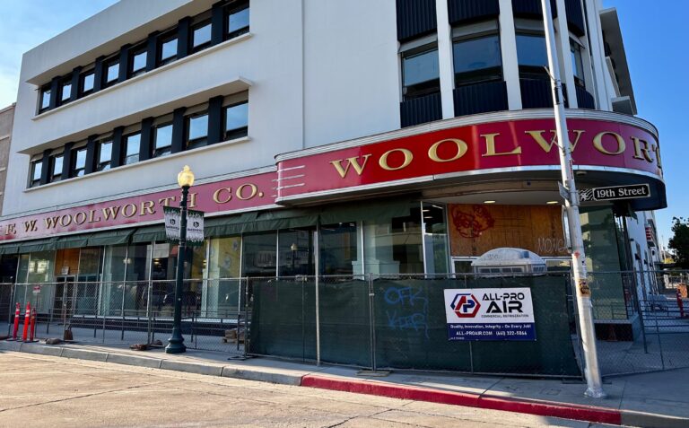 Woolworths building under renovation construction with All-Pro Air, Inc banner posted on the fence surrounding.