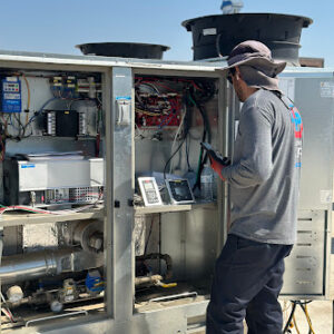 Technician verifying specs on a large commercial rooftop unit.